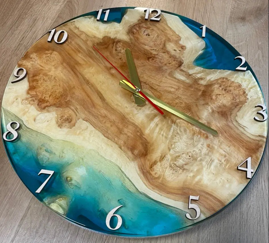 Bovenaanzicht van handgemaakt decoratieve ronde wandklok van wortelhout en levendige oceaanblauwe epoxyhars, klaar om op te hangen.