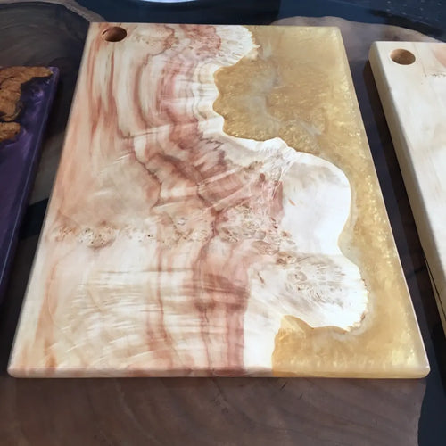 Snijplank van gepolijst epoxyhars en hout met wervelende patronen in crème- en bruintinten, voor een marmereffect. Elegant en verfijnd ontwerp.