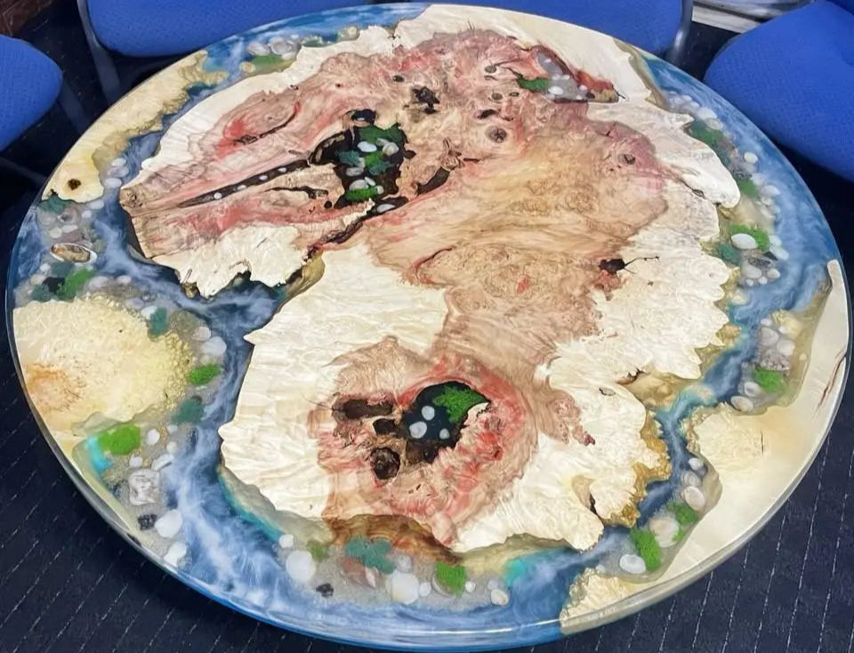 Hoogwaardig esdoorn burl hout en voorzien van gedetailleerde resin art. Een grote esdoorn "eiland" vormt het middelpunt, omringd door turquoise wateren en witte golf-effecten. Kleine eilandjes met gekleurde steentjes, schelpen, mos en zand maken het tafereel compleet.