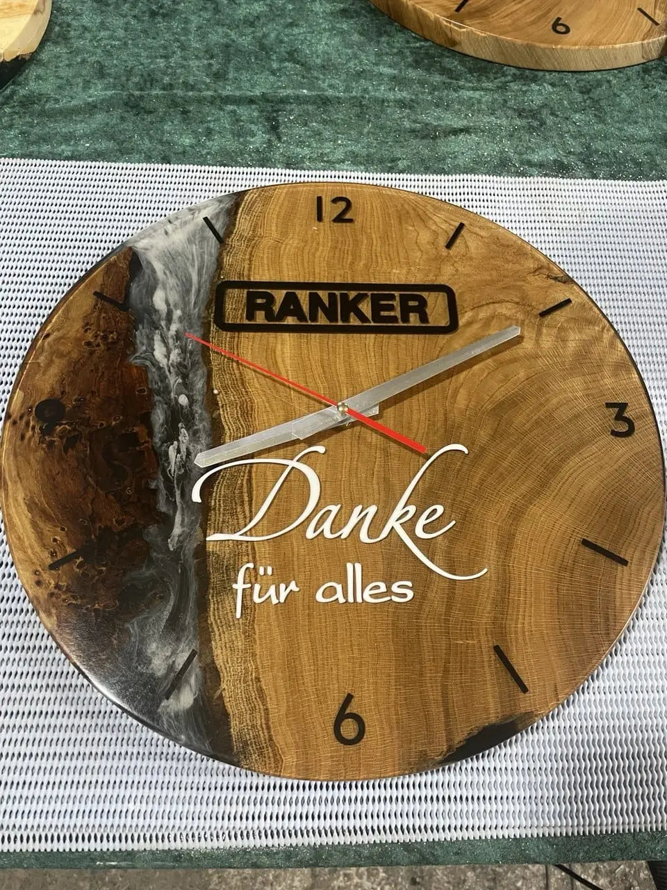 Rustieke houten klok met een riviermotief van kunsthars, gemerkt met "Ranker". Voorzien van stijlvolle zwarte cijfers, rood-zilveren wijzers en "Danke für alles" in elegant schrift.
