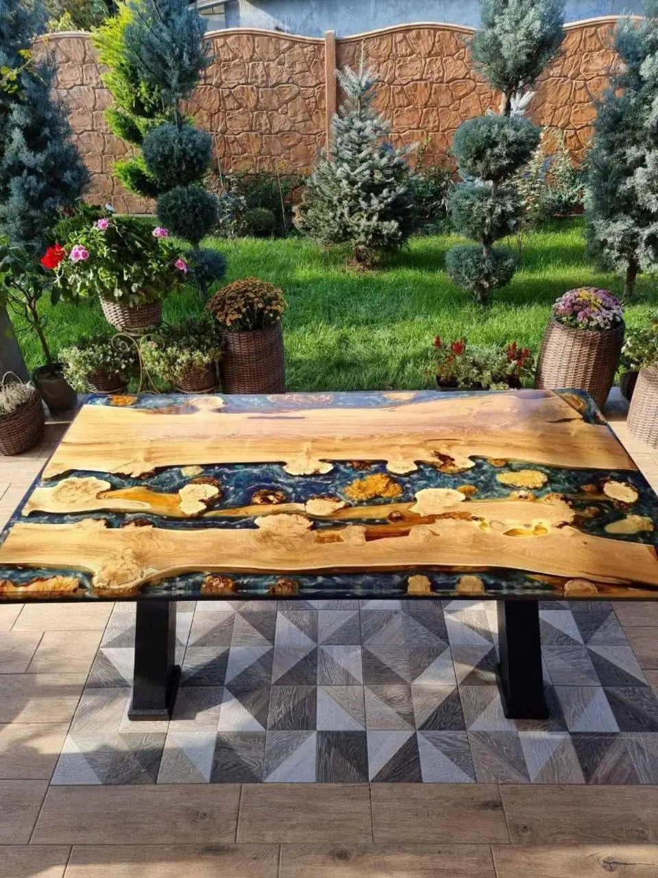 Gladde houten tafel met wervelende patronen van gepolijst zwart hars, die lijken op een zee, wat een rustieke maar toch elegante sfeer creëert.