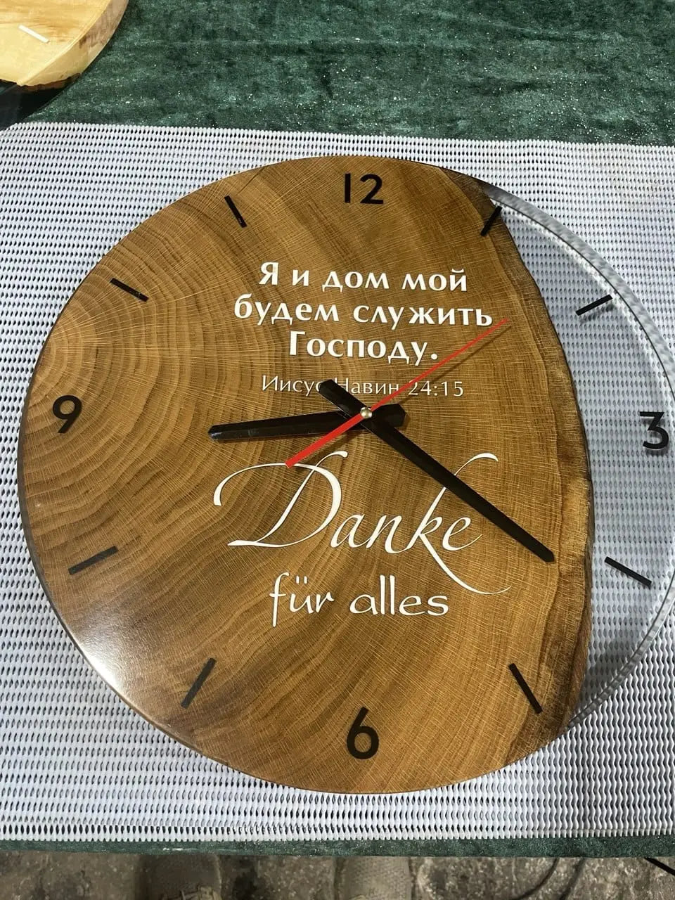 Handgemaakte rustieke houten wandklok met opvallende zwarte cijfers en wijzers, die 12:05 aangeven. Unieke gegraveerde bedankboodschap in het Russisch en Duits. Vintage klok van eikenhout, perfect voor een gezellig, modern of landelijk interieur.