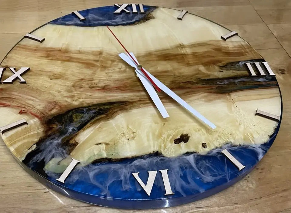 Round wooden wall clock with Roman numerals and vibrant blue epoxy resin detail, featuring white and red hands. Handmade epoxy clock with rustic oak wood design – perfect for modern, artistic home decor.