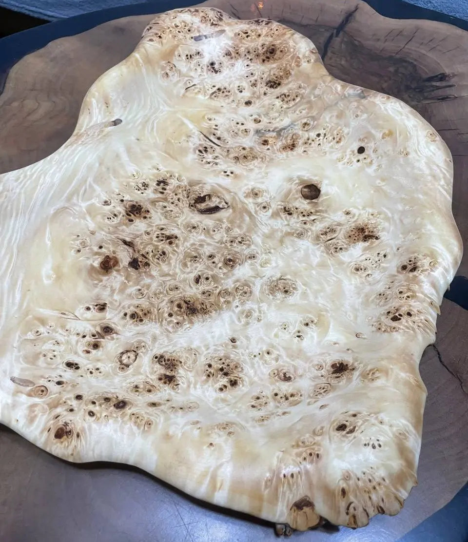 Close-up van een zeer getextureerde houten schaal met ingewikkelde nerfpatronen en wervelende knoesten, op een glad oppervlak. Aardse en organische tinten.