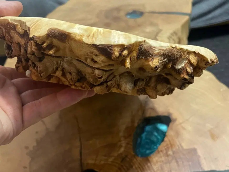 Close-up van een hand die een houten schaal met textuur en ingewikkelde patronen vasthoudt.
