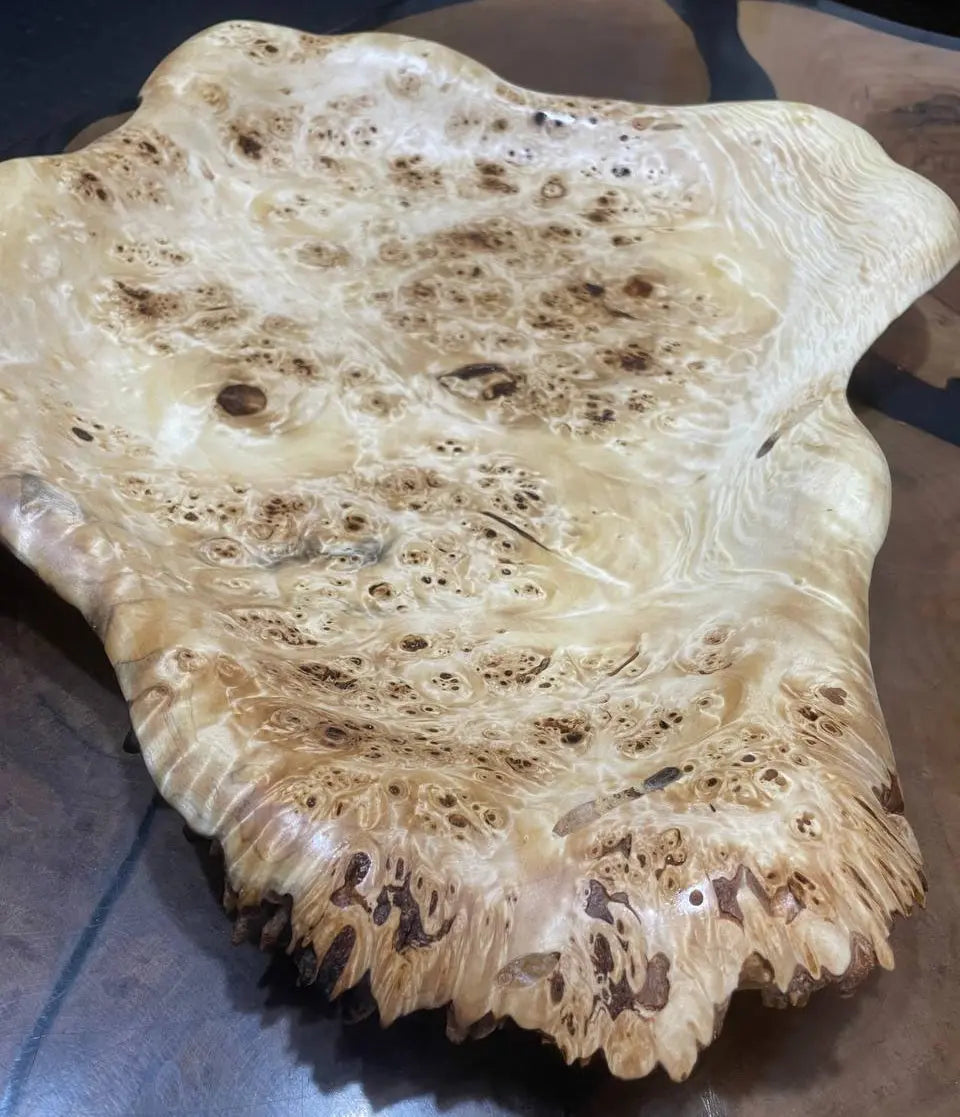 Smooth wooden bowl with intricate burl patterns, featuring rich swirls and knots. Its natural, earthy tones generate a warm, rustic feel.