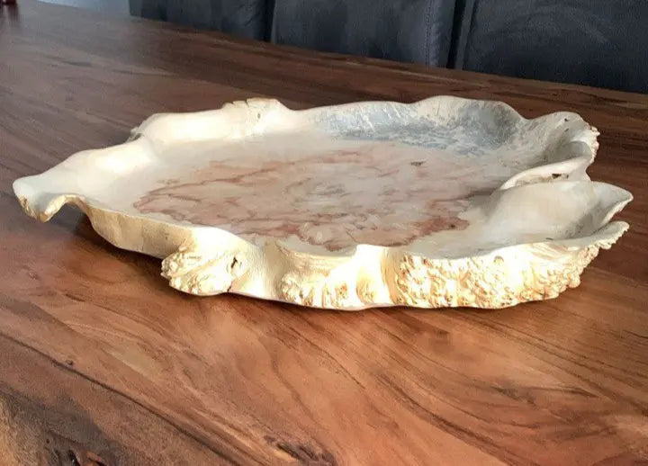 Zijaanzicht van een decoratieve bladvormige schaal kom van esdoornhout op een tafel.