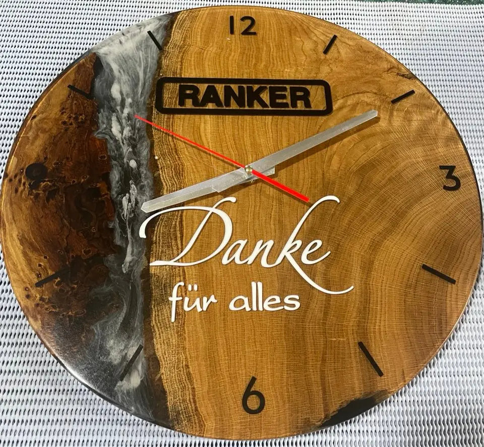 Handgemaakte houten wandklok met zwarte epoxyhars, zilveren en rode wijzers, en gegraveerde tekst 'Danke für alles'.