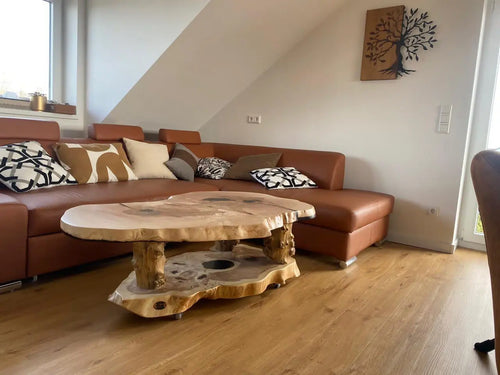 Handgemaakt salontafel van hoogwaardig essenhout. De tafel heeft een vloeiend, geometrisch blad dat rust op een vlak, geometrisch onderstel. De rijke houtnerf, natuurlijke kleurtinten en zachte, matte afwerking geven deze tafel een warme en moderne uitstraling.