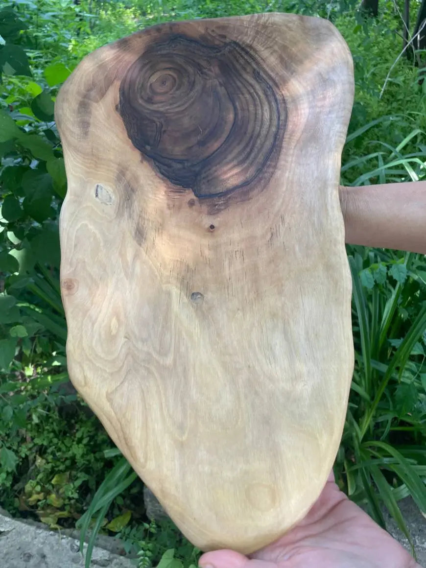 Een houten designplank met een opvallende, door een rode roos geïnspireerde, donkere knoop.