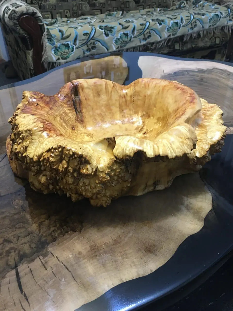 Unique, carved wooden bowl with intricate textures, resting on a glossy, rustic table.