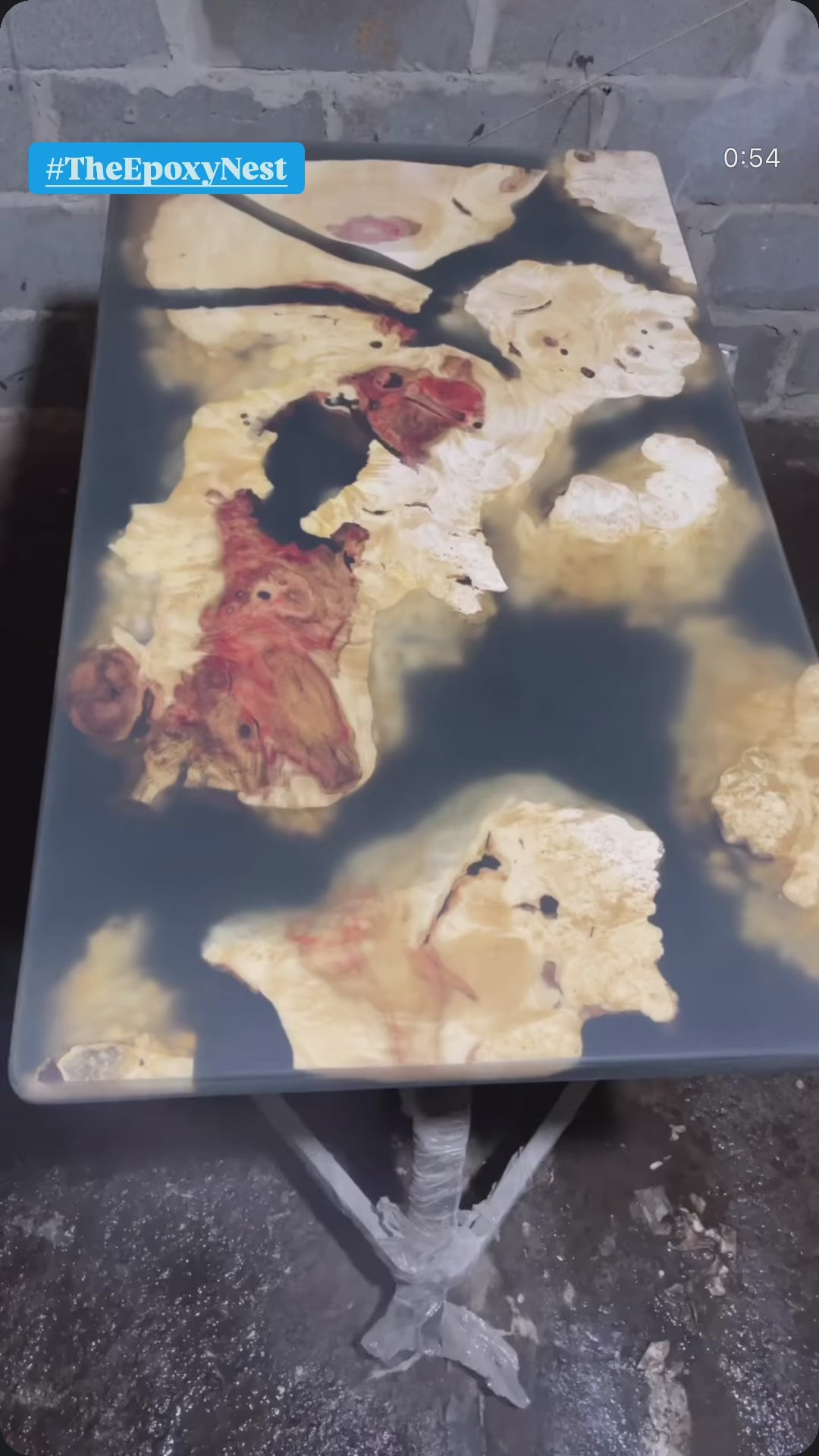 Video van een abstracte tafel van epoxyhars en hout met een organisch, levendig randontwerp, met rode en crèmekleurige houtnerf ingebed in glanzend zwarte hars. Handgemaakt, opvallend meubilair.