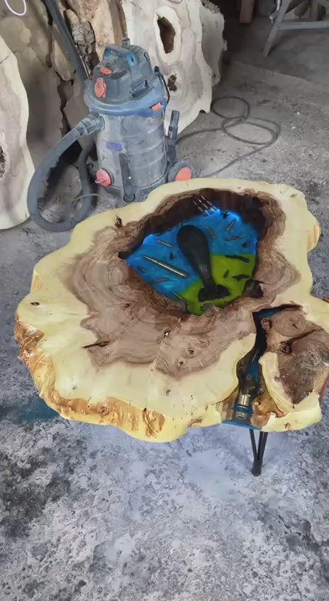 Het tafelblad is handgesneden uit massief iepenhout en afgewerkt voor een natuurlijke, robuuste uitstraling. Wanneer je de ingebouwde verlichting aansluit, komt de compositie echt tot leven: de kogelhulzen glinsteren, het blauw van de epoxy gloeit sfeervol en de contrasten tussen oorlog en kunst worden voelbaar in je interieur.