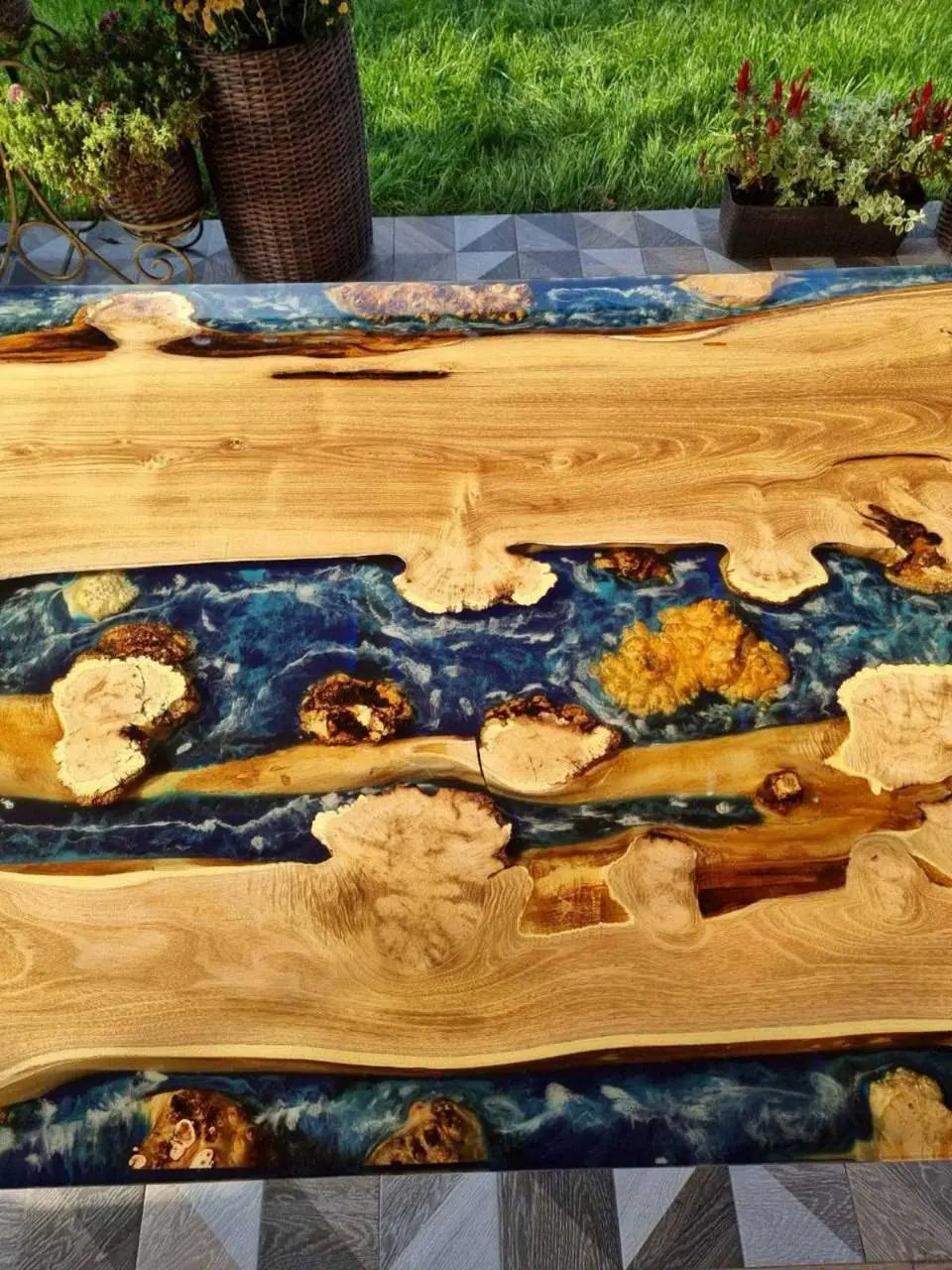 Bovenaanzicht van een gladde houten vergadertafel met wervelende patronen van gepolijst zwart hars en wit hars, die doen denken aan de golven die tegen de kust van het eiland slaan. Dit creëert een rustieke maar elegante sfeer.